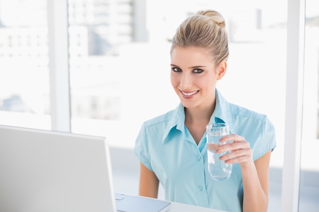 Smiling well dressed businesswoman holding water