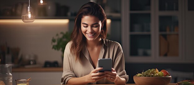 Smiling white woman at kitchen table using cellphone for online activities during meal empty area