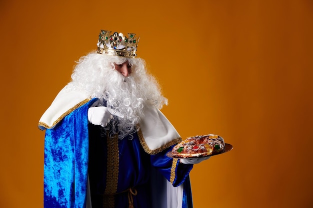 Smiling Wise Man holding a quotroscon de reyesquot in his hand on an orange background