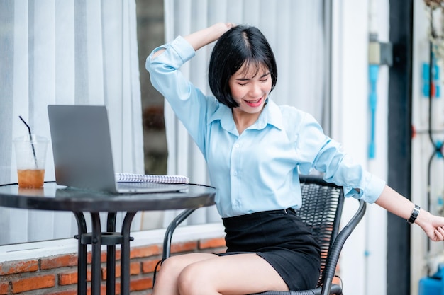 Smiling with dental braces Stretching Relaxation Resting of asian freelance people business female casual working with laptop computer with coffee cup and smartphone in coffee shop the background