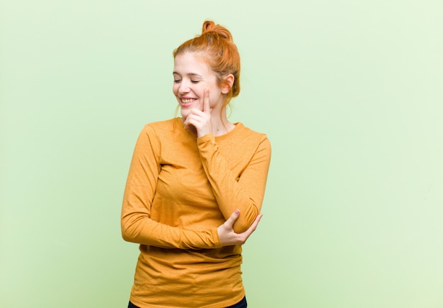 smiling with a happy, confident expression with hand on chin, wondering and looking to the side