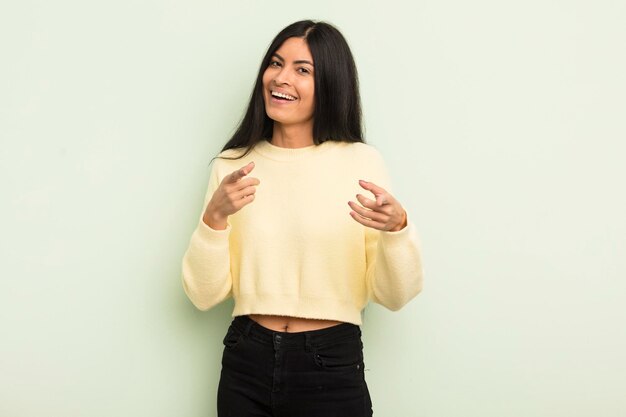 Smiling with a positive successful happy attitude pointing to the camera making gun sign with hands