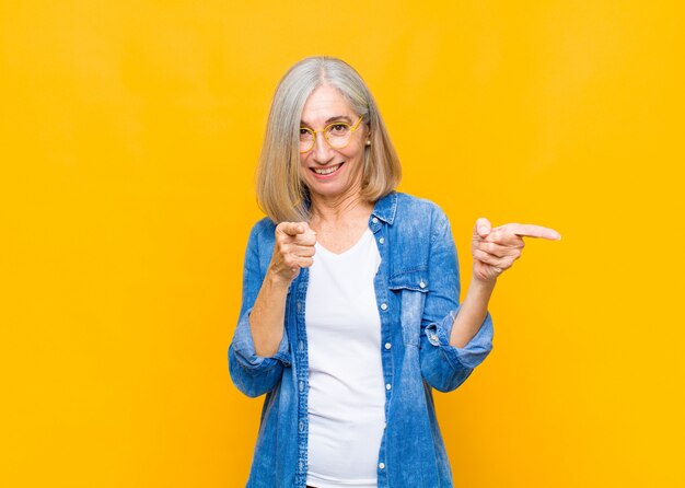 smiling with a positive, successful, happy attitude pointing at front, making gun sign with hands