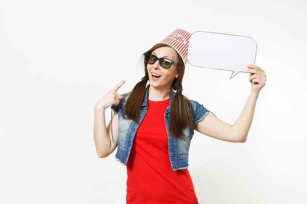 Smiling woman in 3d glasses with bucket for popcorn on head watching movie film, poiting index finger on say cloud with place for text, copy space isolated on white background. Emotions in cinema.