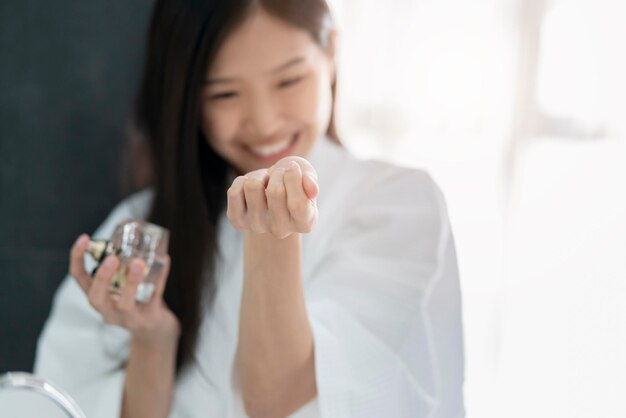 写真 家で香水を塗っている笑顔の女性