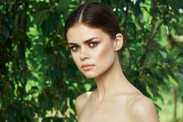 Smiling woman attractive look bare shoulders green leaves closeup