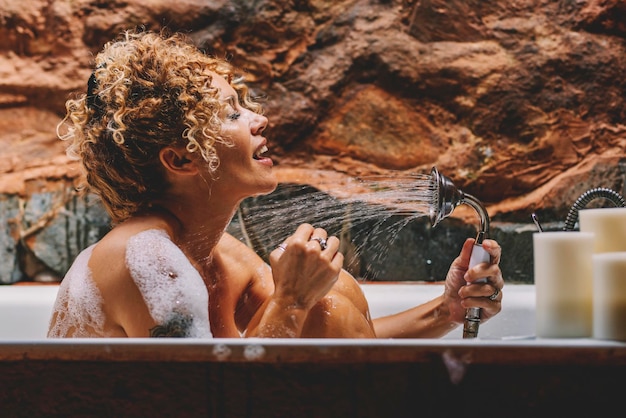 写真 浴槽で風呂を浴びている笑顔の女性