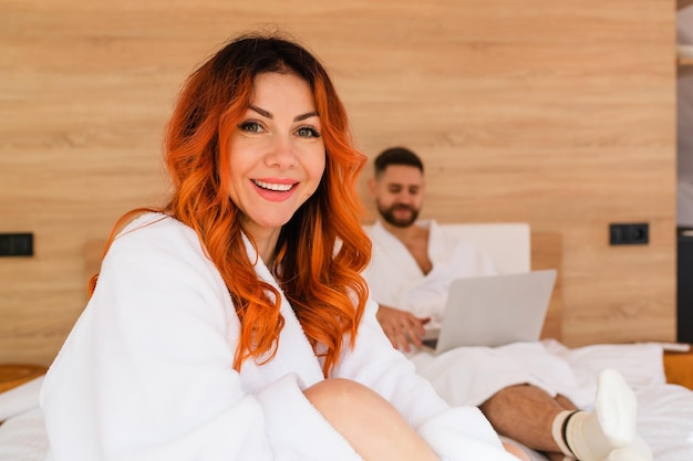 Smiling woman in a bathrobe sitting on bed