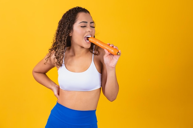 Smiling woman bites carrot. Isolated studio portrait