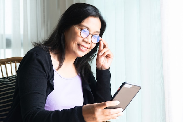 Photo smiling woman black long hair sitting holding smartphone and communicate with family