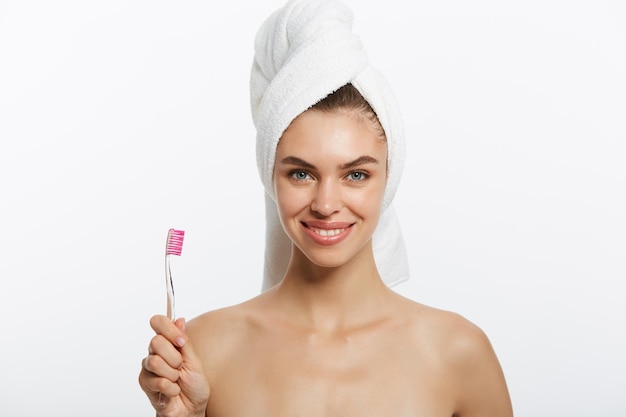 Smiling woman brushing her teeth with towel on her head a great smile