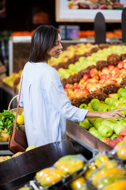 Smiling woman buying fruits in organic section