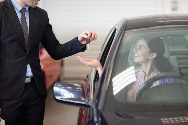 Smiling woman in a car taking keys