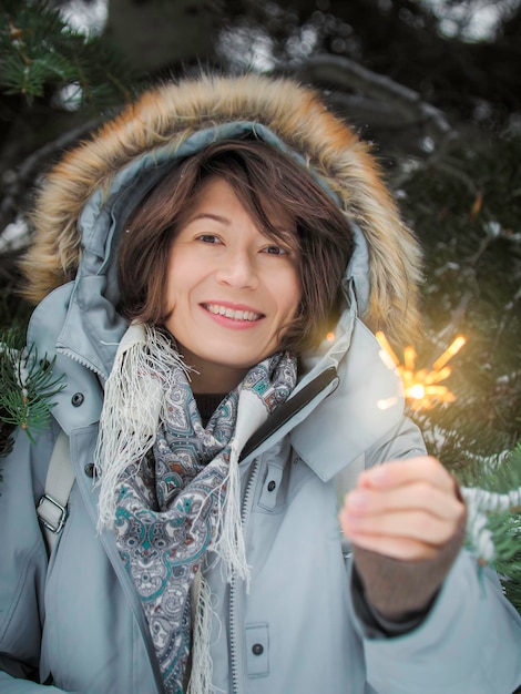 Foto donna sorridente celebra il natale o il capodanno con fuochi d'artificio tradizionali