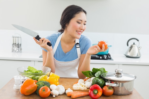 Smiling woman chopping vegetables in kitchen