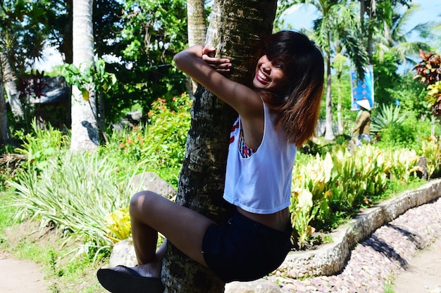 Photo smiling woman climbing tree at park