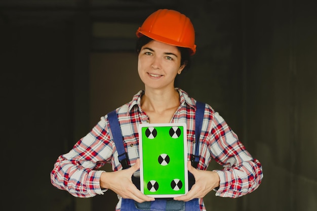 Smiling woman construction manager holding tablet device with green screen Architect or designer