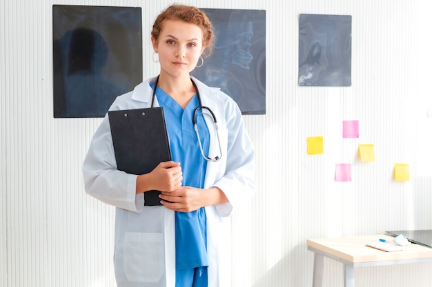 Smiling woman doctor possing and wearing a stethoscope on hospital room.