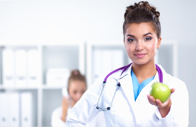 Foto medico sorridente della donna con una mela verde