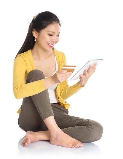 Smiling woman doing online shopping while sitting against white background