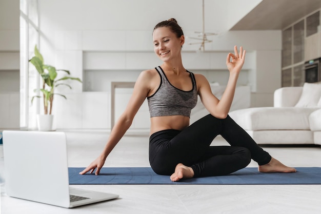 Donna sorridente che fa esercizio di yoga a casa