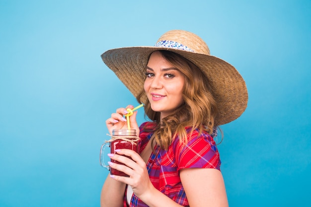 Smiling woman drink red juice. studio portrait with blue background and copy space.