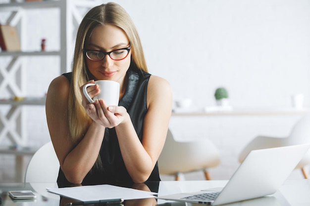 職場でコーヒーを飲みながら笑顔の女性