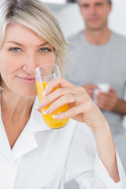 Улыбка женщины, пить апельсиновый сок в кухне