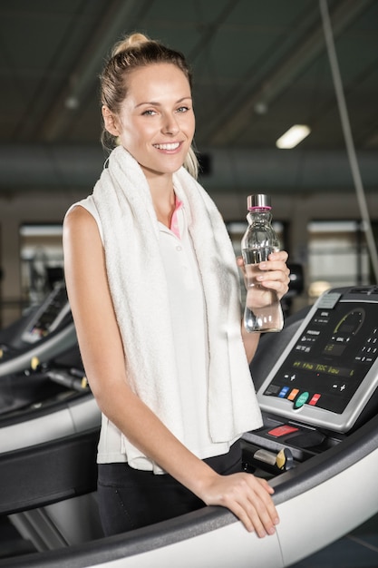 Smiling woman drinking water in the gym