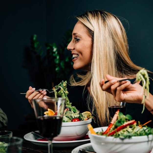 smiling woman eating salad on table at home