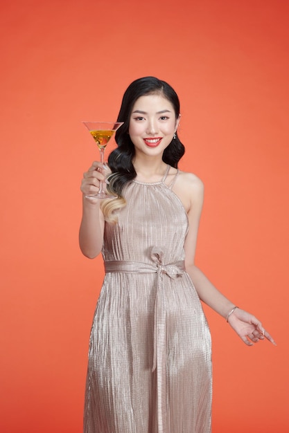 Smiling woman in elegant sequin dress holding glass of wine and enjoying new year party