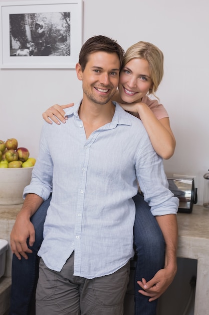 Smiling woman embracing man from behind at home