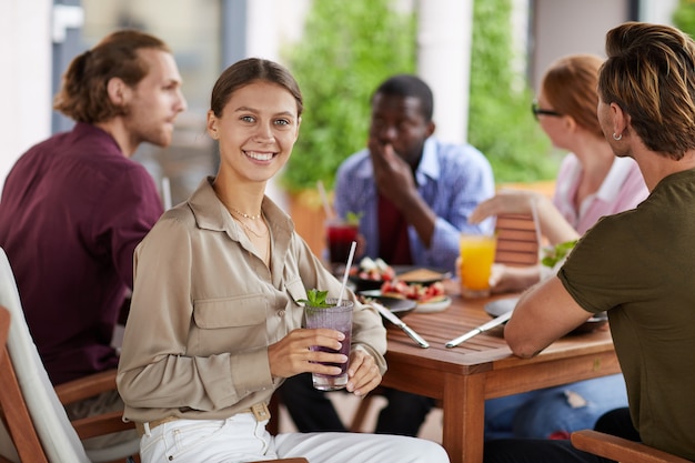 Donna sorridente che gode del pranzo con gli amici in caffè