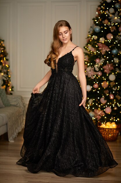 Smiling woman in evening dress over christmas tree