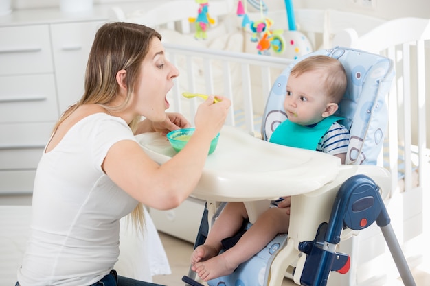 Donna sorridente che allatta il suo bambino nel seggiolone in soggiorno