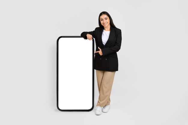 Photo smiling woman in formal presenting blank smartphone screen