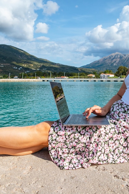 Smiling woman freelancer working on laptop outdoors at city harbor copy space