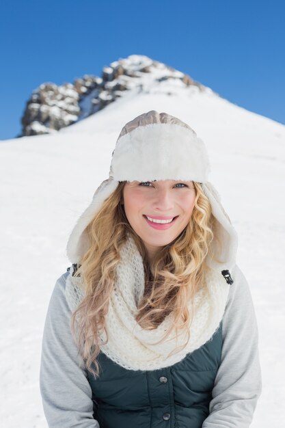 Smiling woman in front of snowed hill and clear blue sky