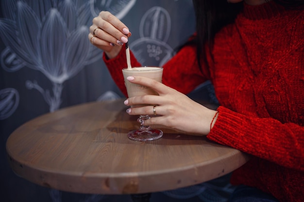 カフェでコーヒーのカップと暗いインテリアの夜の集まりに座って良い気分で笑顔の女性