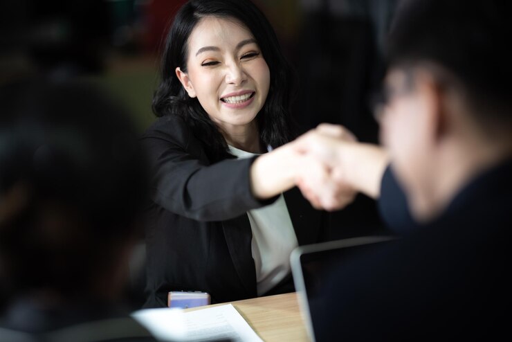 Photo 미소 짓는 여자 는 사무실 책상 에서 동료 와 악수 하고 있다