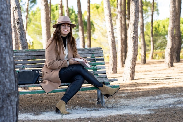 Photo smiling woman in hat reading in nature