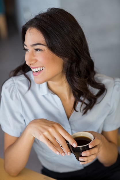 Donna sorridente che mangia tazza di caffè