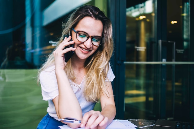 Smiling woman having phone conversation and checking planner