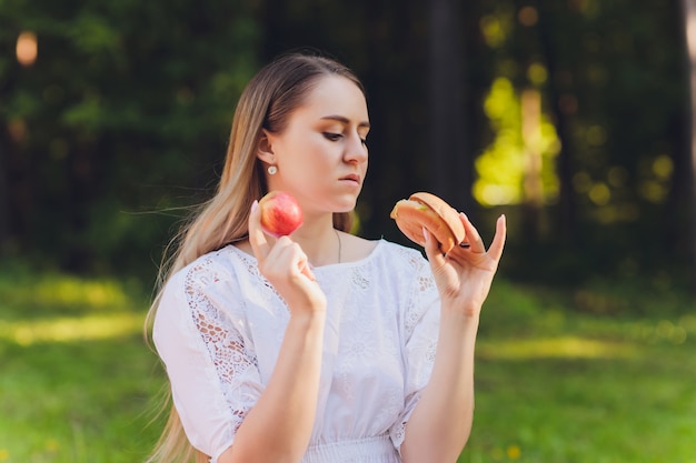 屋外でリラックスした昼食休憩を持っている笑顔の女性、彼女は草の上に座って食べています。