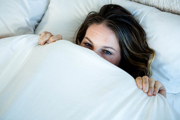 smiling woman hiding behind her blanket