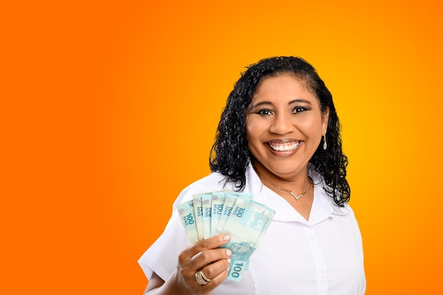 Photo smiling woman holding 100 reals notes in her hands points to the money in her hand brazilian money