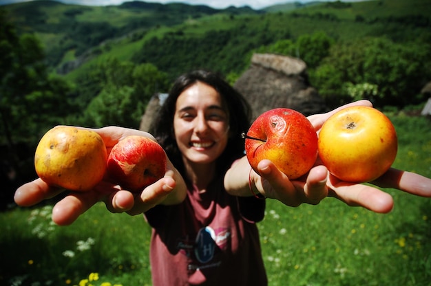 Foto donna sorridente con le mele in mano sulla montagna