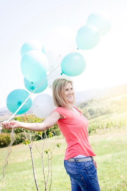 Photo smiling woman holding balloons while standing against sky