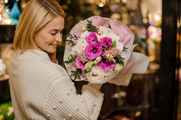 Smiling woman holding a bouquet of tender pink and purple color flowers