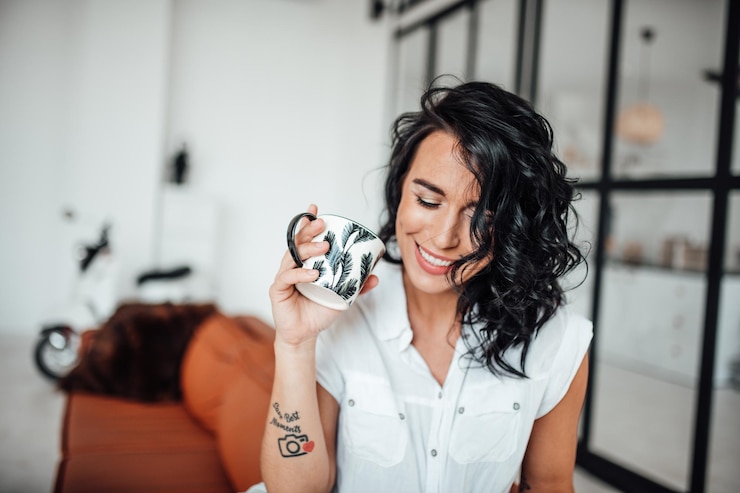 Photo smiling woman holding coffee cup sitting at home